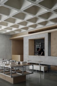 A concrete bookstore display area with metal shelving and stacks of books.