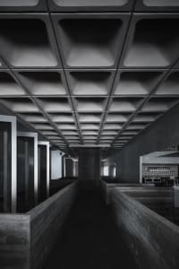 A photograph of a corridor with industrial decor, featuring concrete walls and ceiling.