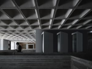 A minimalist office interior featuring concrete walls and a textured ceiling panel.