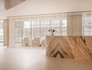 A minimalist reception desk with a marble countertop and a vase with flowers.