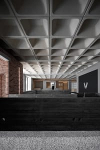 A modern lobby with a concrete ceiling and floors, featuring geometric shapes and a minimalist design.
