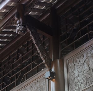A close-up view of intricately carved wooden panels and beams in a traditional architectural setting.
