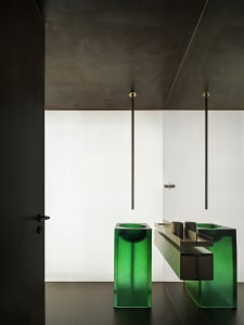Industrial-style bathroom with green glass sinks and minimalist design.