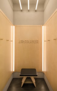 Modern minimalist clothing retail store with wooden walls and illuminated signage.