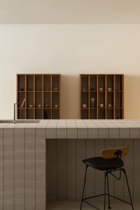 Modern minimalist kitchen with a tiled countertop and wooden shelves.