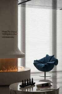 Modern living room interior with textured concrete fireplace and blue upholstered chair.