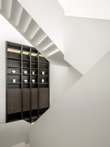 A modern staircase with white concrete steps and black wooden railings.