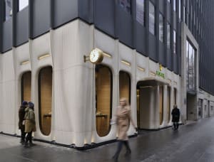A modern Rolex storefront with concrete exterior and golden accents.