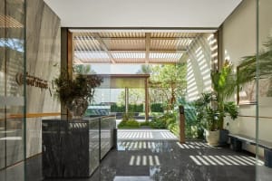 A modern lobby with glass walls and a garden view.