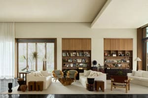 A modern living room featuring white sofas, wooden cabinets, and leather chairs.