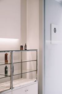A modern showroom interior featuring glass shelves, metal accents, and a fluffy white surface.