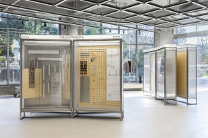 An exhibition display featuring metal and wood prop-building elements in a modern, industrial setting.