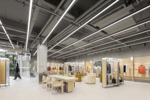 A minimalist retail storefront with a concrete floor and ceiling, featuring display racks and seating areas.