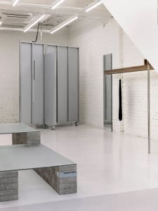 Modern minimalist storefront with concrete elements and white walls.