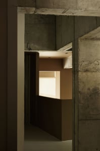 A minimalist interior space with concrete walls and ceiling, featuring a bright light source.