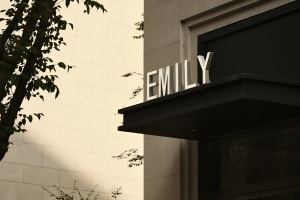 A large, modern building entrance sign made of metal with the name "EMILY" in capital letters.
