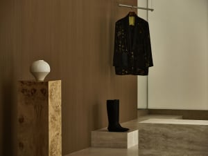A minimalistic interior space featuring a stylish black jacket and a white vase on wooden pedestals.