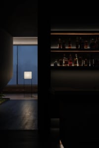 A modern bar space with glass shelves containing various bottles of alcohol and a sleek, contemporary design.