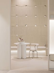 A minimalist interior space with a concrete wall and white furniture.