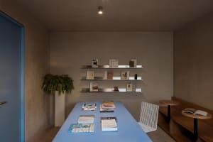 A spacious, modern bookshop featuring minimalist concrete shelving and metal accents.