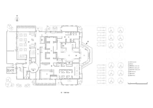 Floor plan of an office building depicted on paper, showing various functional zones and furniture arrangements.
