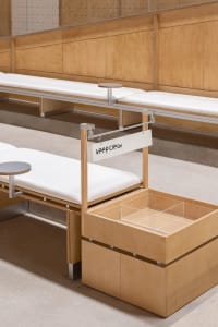 A modern minimalist bench with built-in storage unit made of light wood.