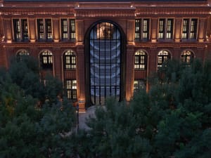 A modern library facade with brick and glass materials, illuminated at night.