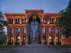 A modern building with brick exterior and large glass doors at dusk.