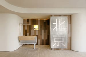 A modern office interior featuring minimalist design elements such as wood, metal, and textured tiles.