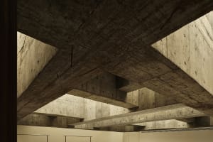 An interior space with modern design, featuring concrete beams and walls.
