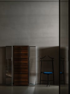 Modern interior design featuring a wooden wardrobe and a black valet stand with blue cushion.