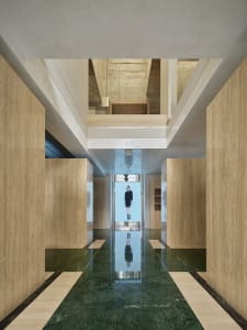 Modern living room featuring concrete walls and green marble flooring.