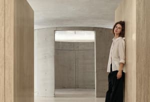 A minimalist interior scene featuring concrete walls and a light source through a window.