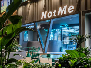 Modern glass storefront of a coffee shop with sleek metal accents and concrete flooring.