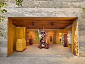 A wooden retail store interior with clothing racks and display shelves.
