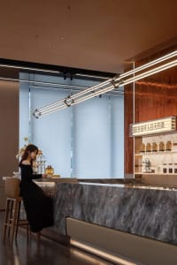 A stylish modern coffee bar with sleek marble countertops, illuminated by contemporary lighting fixtures, and featuring a gla