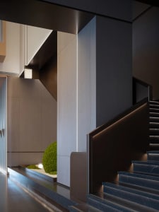 A modern staircase featuring marble treads and concrete walls with integrated lighting.
