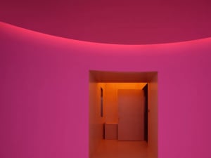 A minimalist room with pink walls and a warm light source.