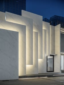 Modern storefront with illuminated marble columns at night.