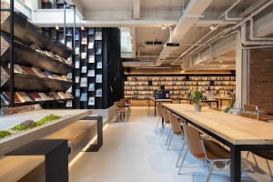 A modern industrial-style library with exposed brick walls, concrete flooring, and metal shelving.