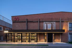 A commercial exterior with brick walls and concrete structures, featuring large glass windows and a black awning.