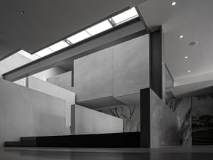 A modern lobby with concrete walls and floors, featuring sleek, minimalist design elements.