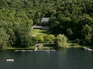 A modern residential lakeside lawn with a dock and surrounding greenery