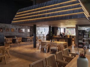 Modern industrial cafe interior with wooden tables, chairs, and concrete flooring.