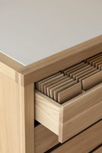A minimalist furniture design featuring oak wood, with details of the joinery and drawer system.