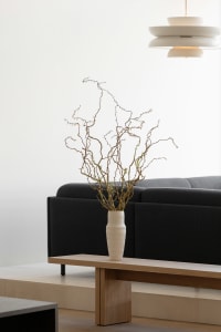 Modern living room featuring a low-profile sofa, wooden coffee table, concrete floor, and minimalist lighting fixtures.
