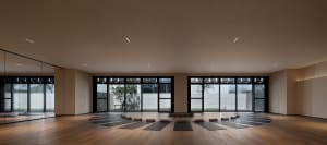Yoga mats arranged in a circle on a hardwood floor in a minimalist yoga studio.