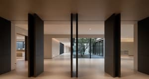 A modern office space featuring glass walls and wooden columns, creating a sleek and contemporary environment.