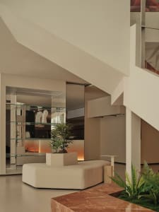 A modern living room with concrete and marble surfaces, featuring a glass planter.