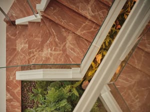 A modern residential corridor featuring marble stone flooring and a living greenery garden.